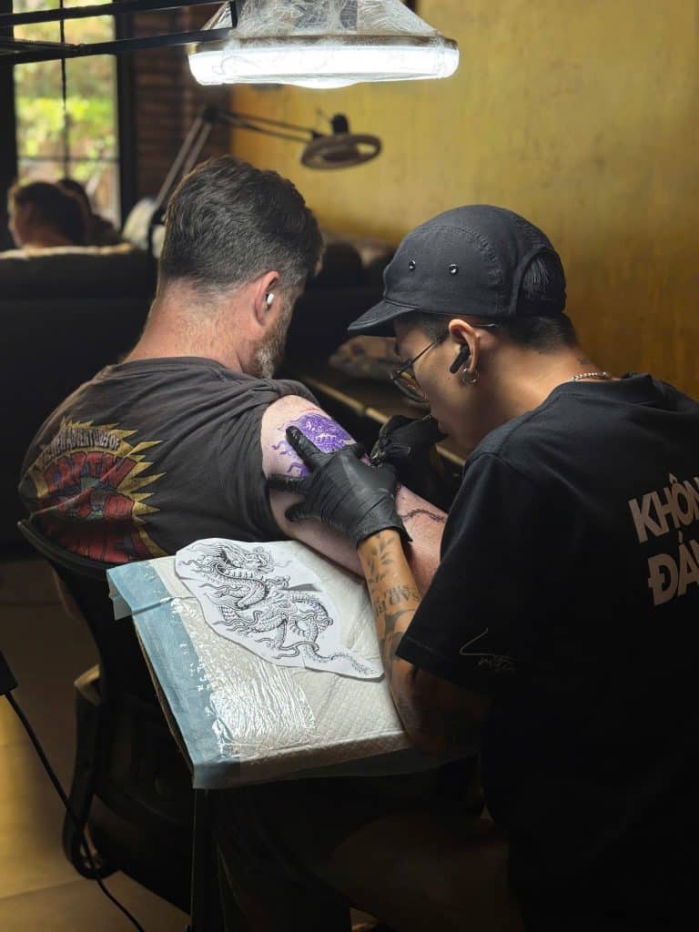 Tattoo artist creating a custom Vietnamese dragon tattoo at Tattoo Station Hoi An
